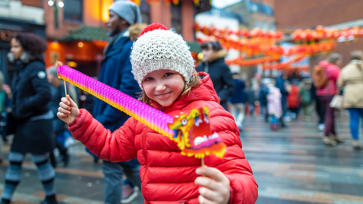 YOung girl poses with Chinese dragon at Lunar New Year Festival for the yearbook